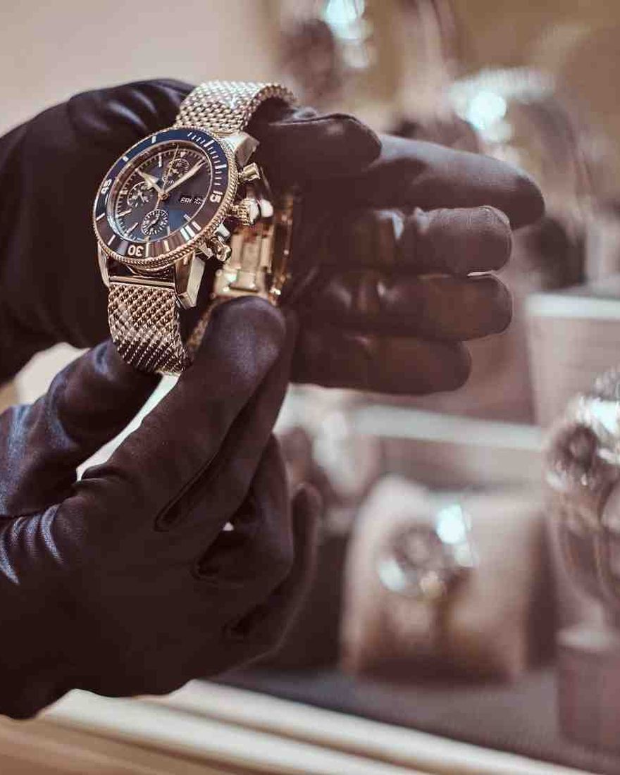 A Conduit Pawn appraiser examining a luxury watch at the counter